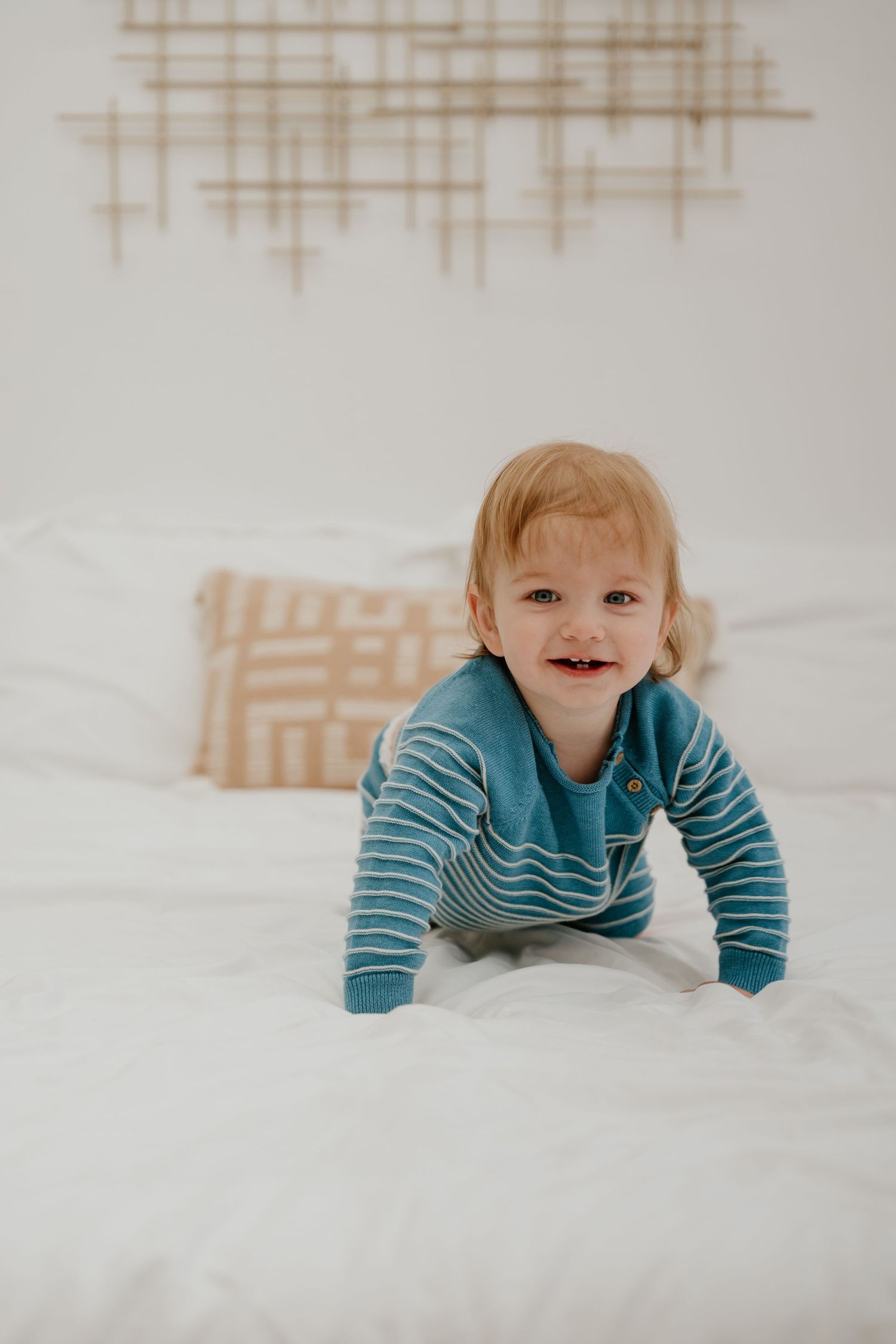 A series of four images showing a small child in a blue striped shirt lying on white bedding.