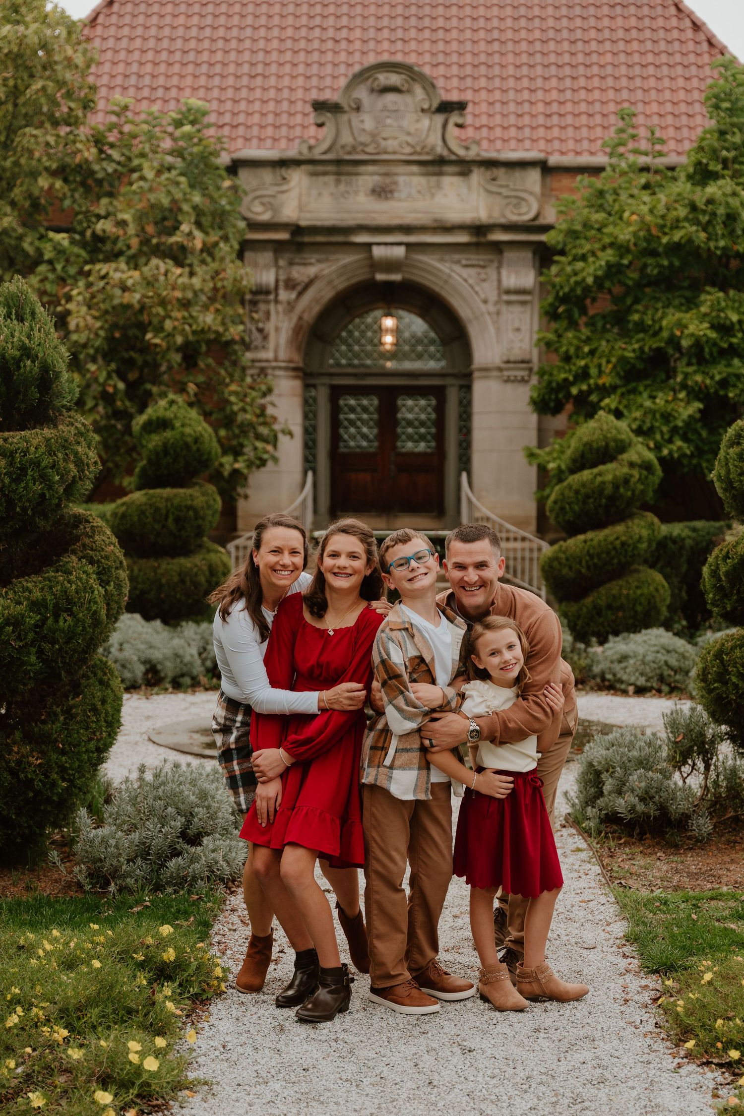 A group sits together on a stone path surrounded by manicured garden landscaping in warm autumn tones.