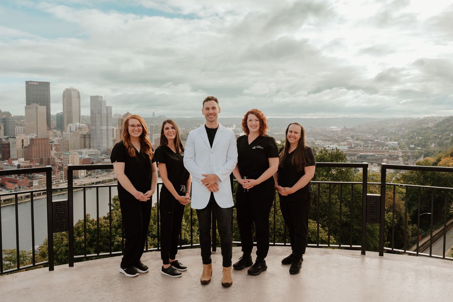 Group poses together on scenic overlook with Seattle skyline and Space Needle visible in background.