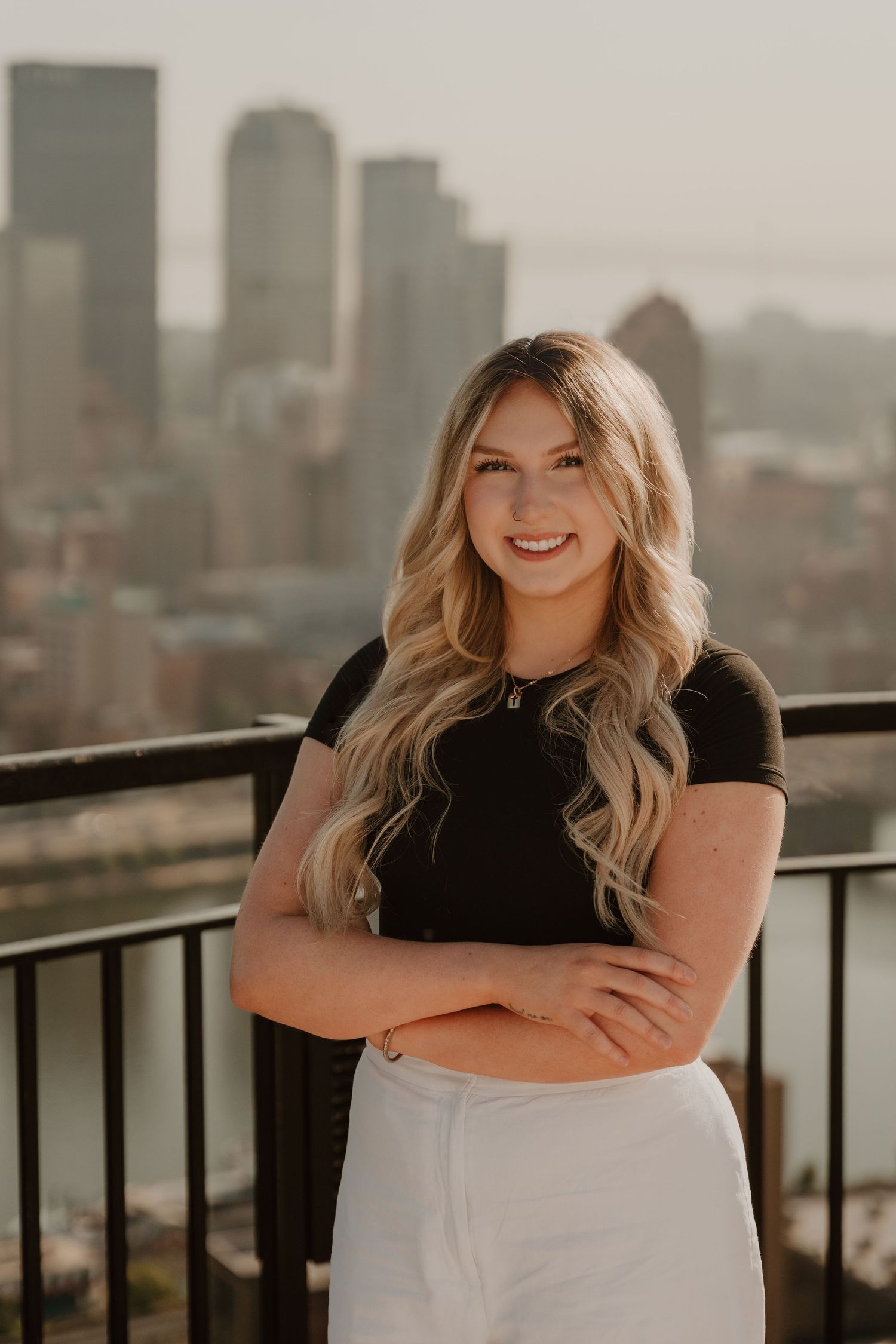 Professional lifestyle portrait series with city skyline backdrop showing relaxed poses against urban railing at sunset.