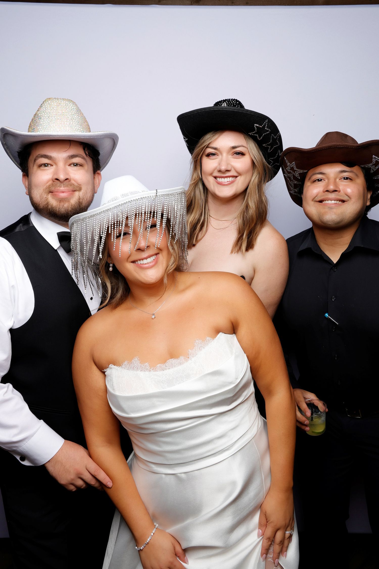 Party guests in western attire and cowboy hats pose playfully for photo booth shots.