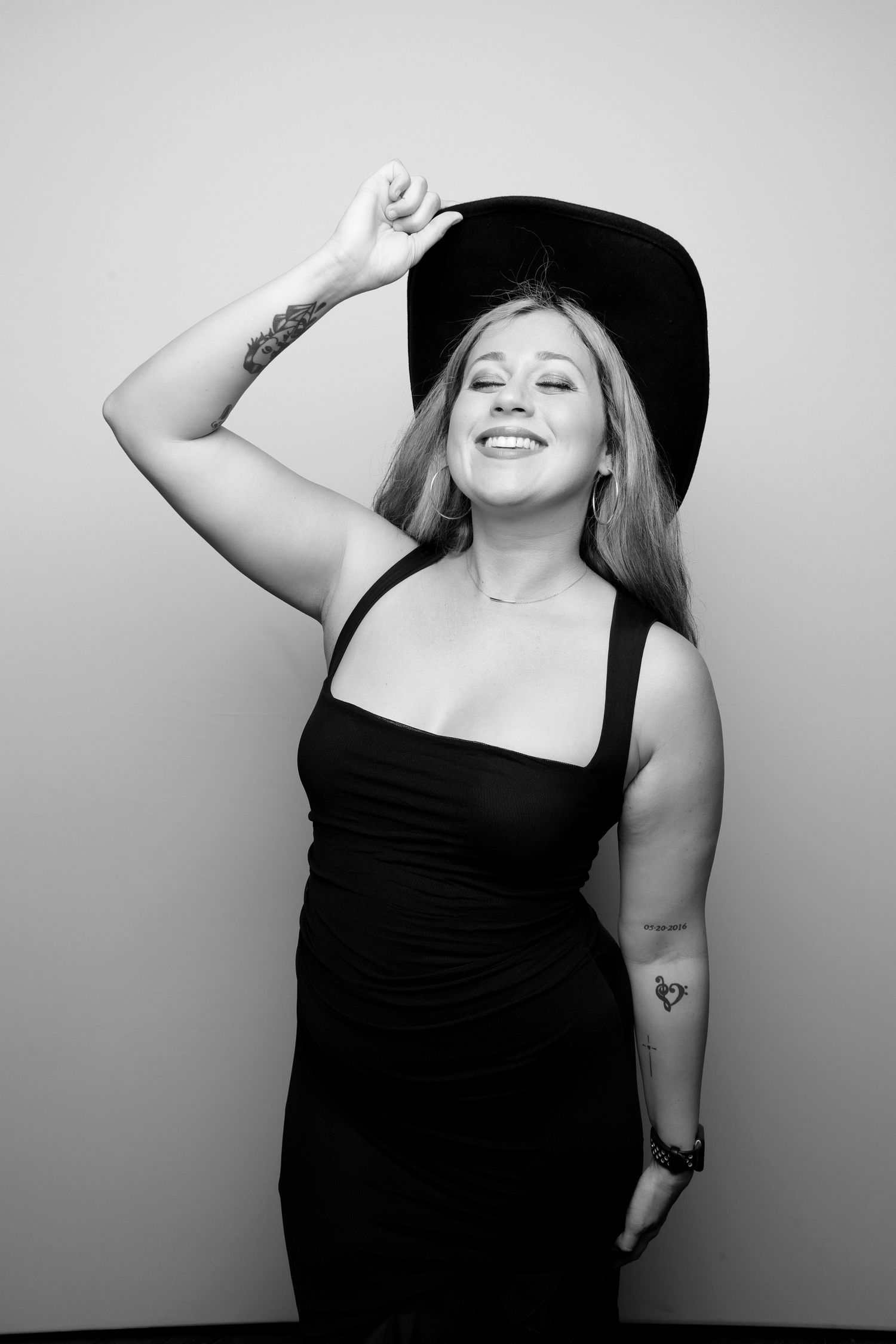 Person in black dress and wide brim hat poses expressively in a photo booth sequence.