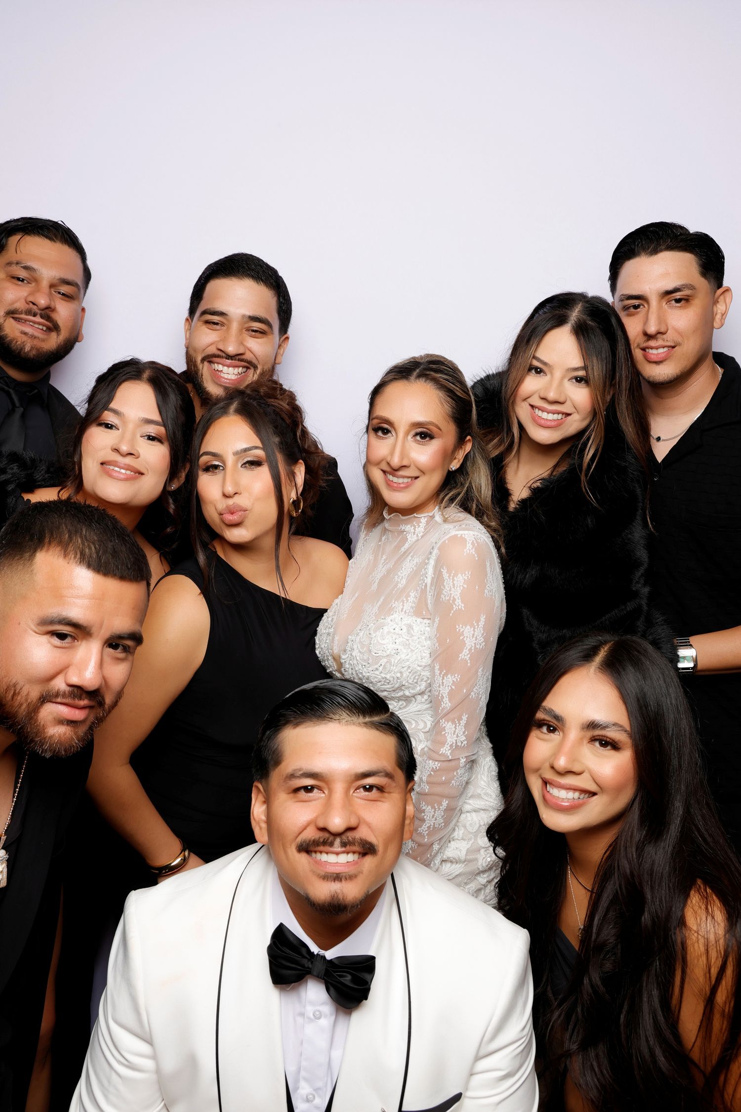 A festive group in formal attire poses together at a photo booth celebration with black and white outfits.