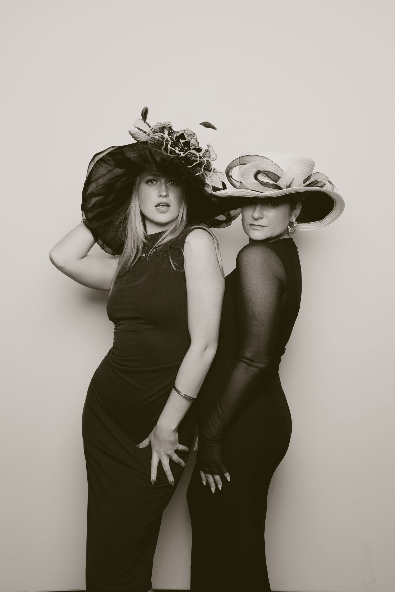 Artistic black and white photo series showing two people in black outfits posing dramatically against a light background.