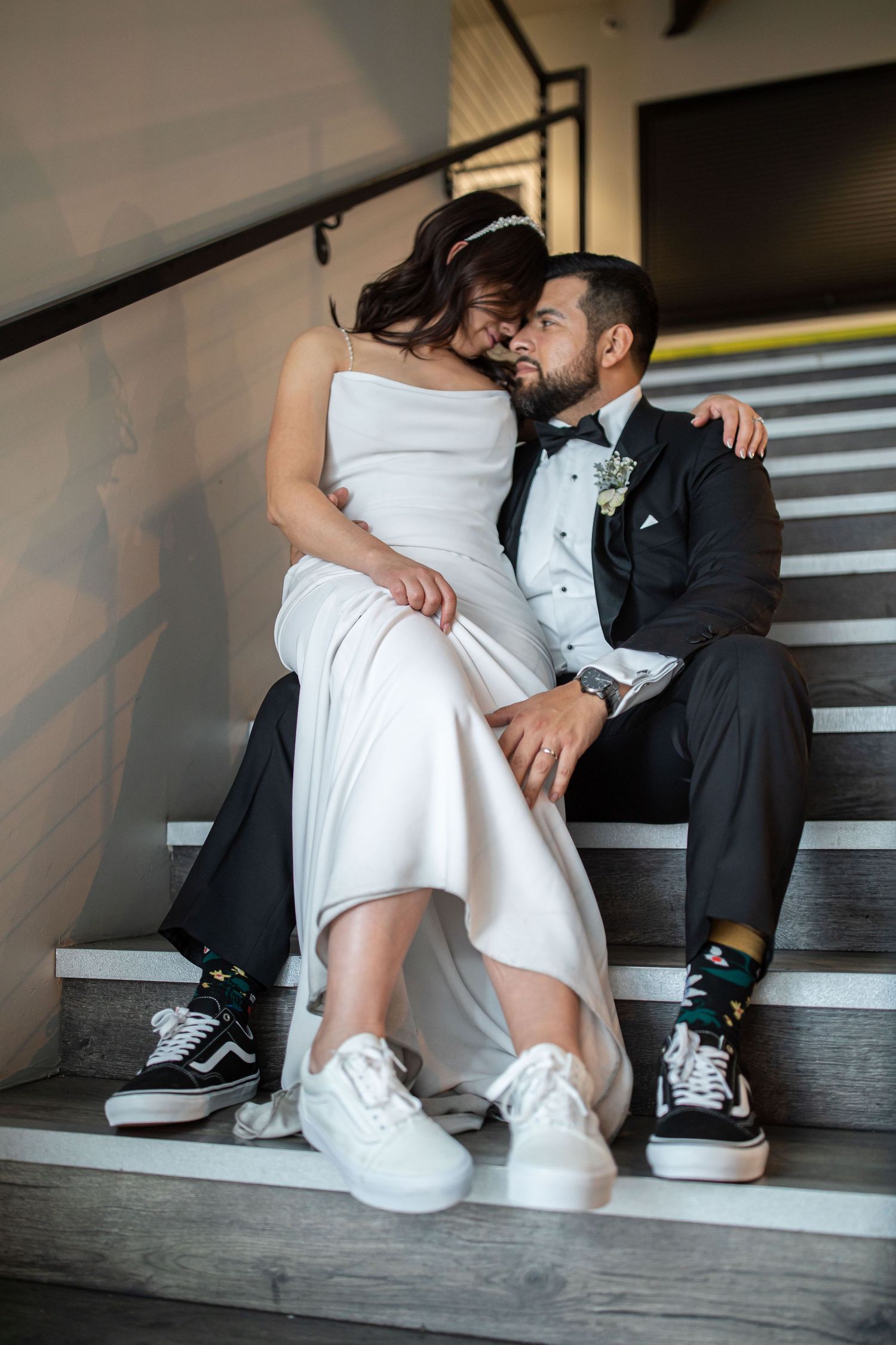 Couple sharing tender moments on industrial staircase in wedding attire.