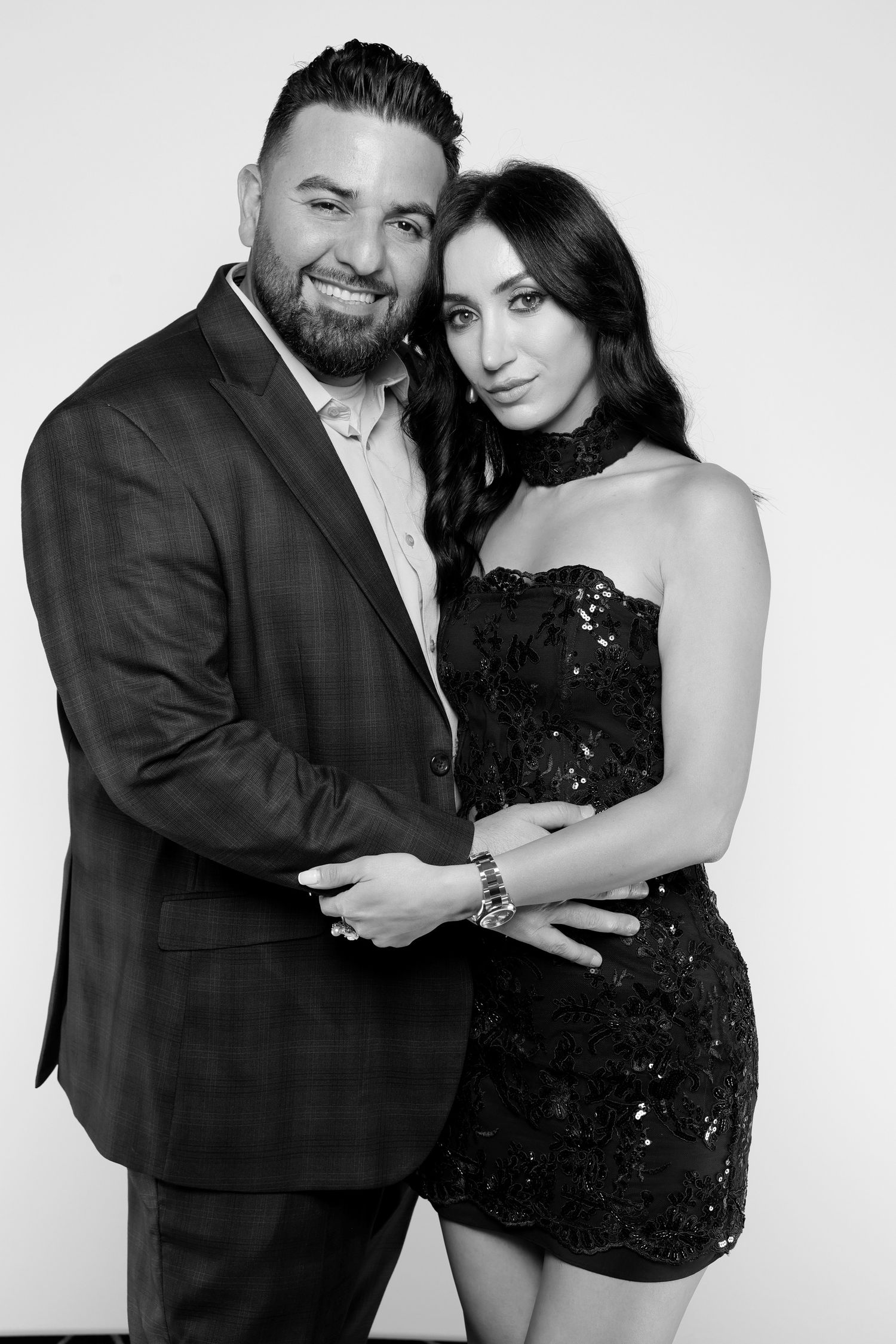 Black and white photo of an elegant couple posing together, man in suit and woman in sequined dress.