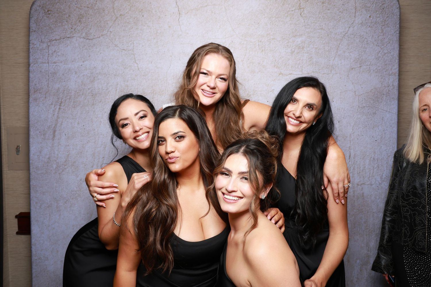 Group photo booth session showing friends posing and laughing together against grey background.