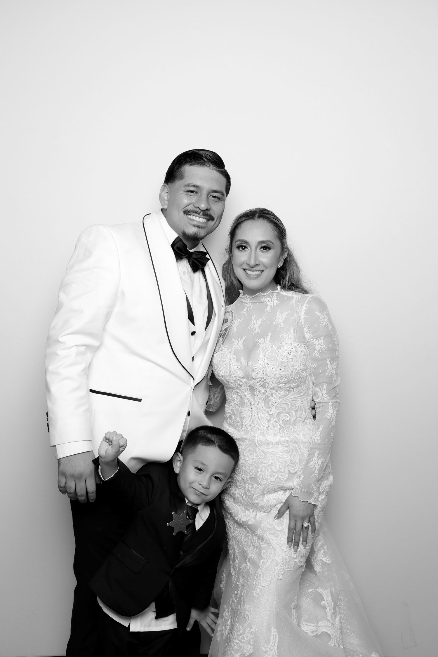 Family in formal attire poses together in black and white photo booth shot.
