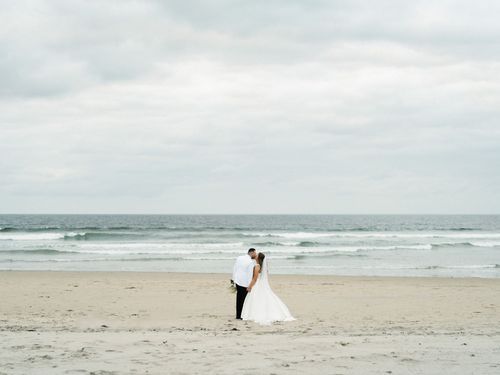 A series of romantic beach wedding photos showing a couple walking along the shoreline on their special day.