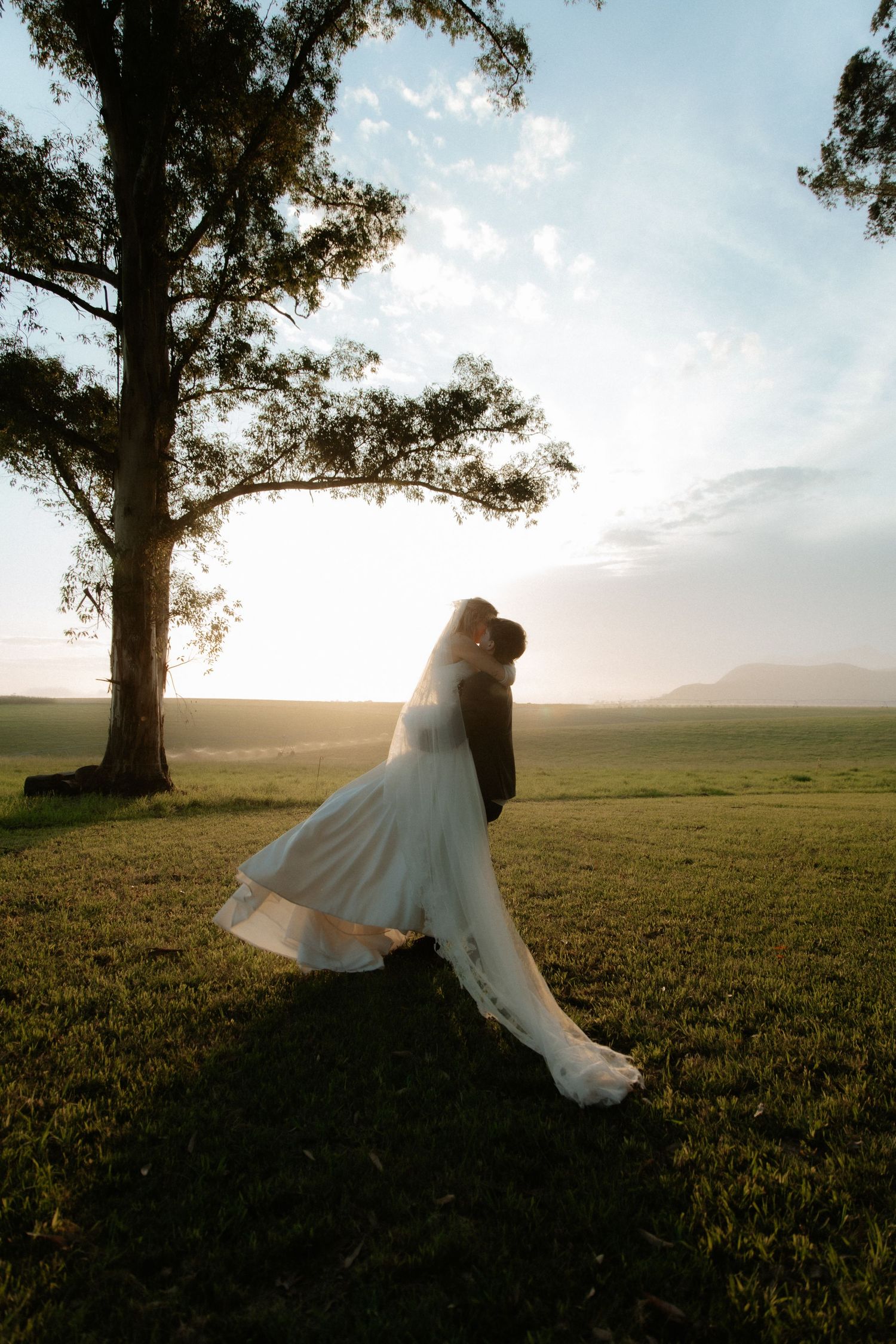 Bride and groom embracing in a sunlit field at golden hour, Garden Route wedding photo and film