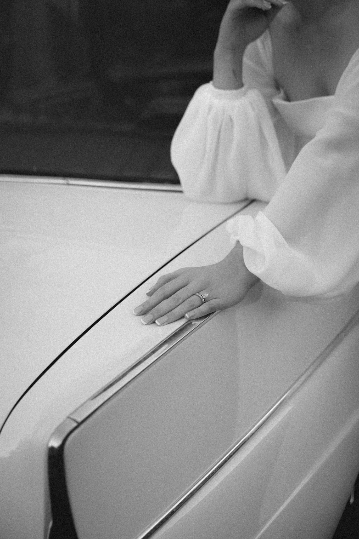 Bride with engagement ring resting arm on vintage car, Garden Route engagement photographer