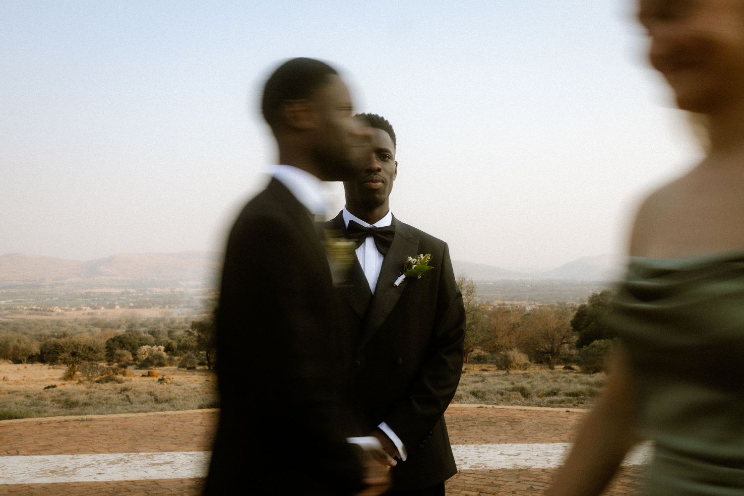 Groom in black tuxedo with boutonniere outdoors with scenic Garden Route background