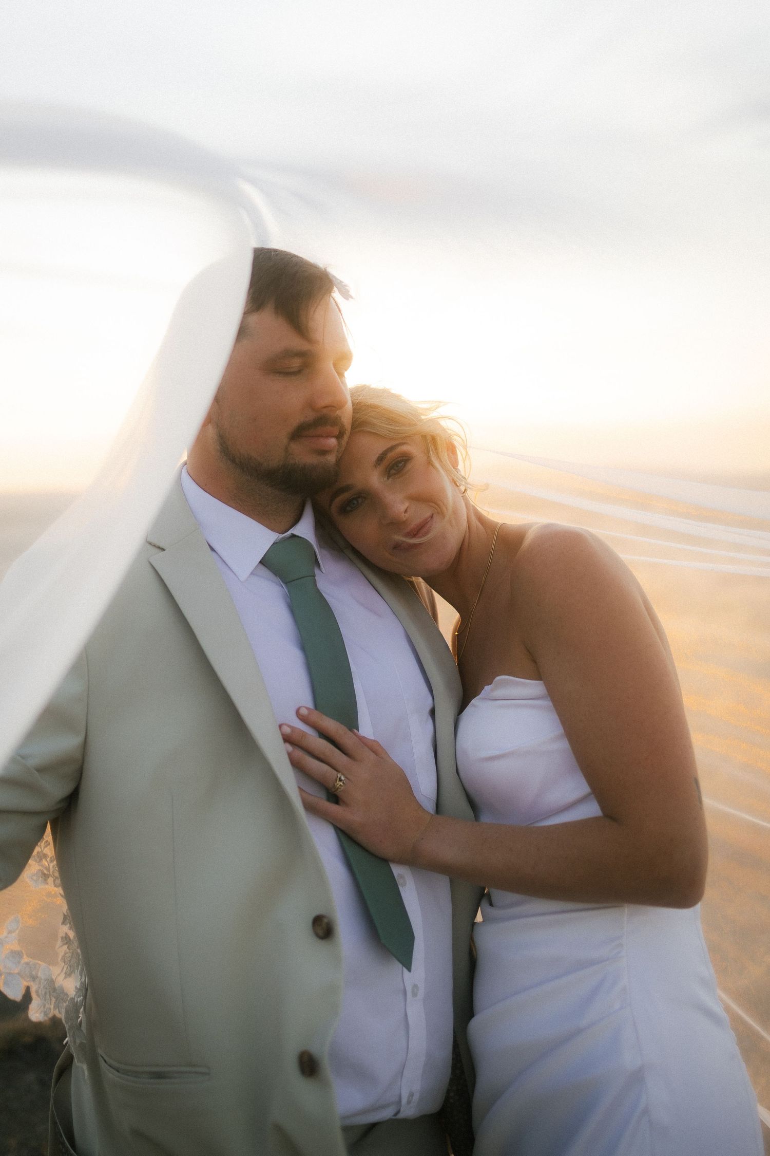 Couple embracing at sunset with flowing veil, Garden Route engagement photographer
