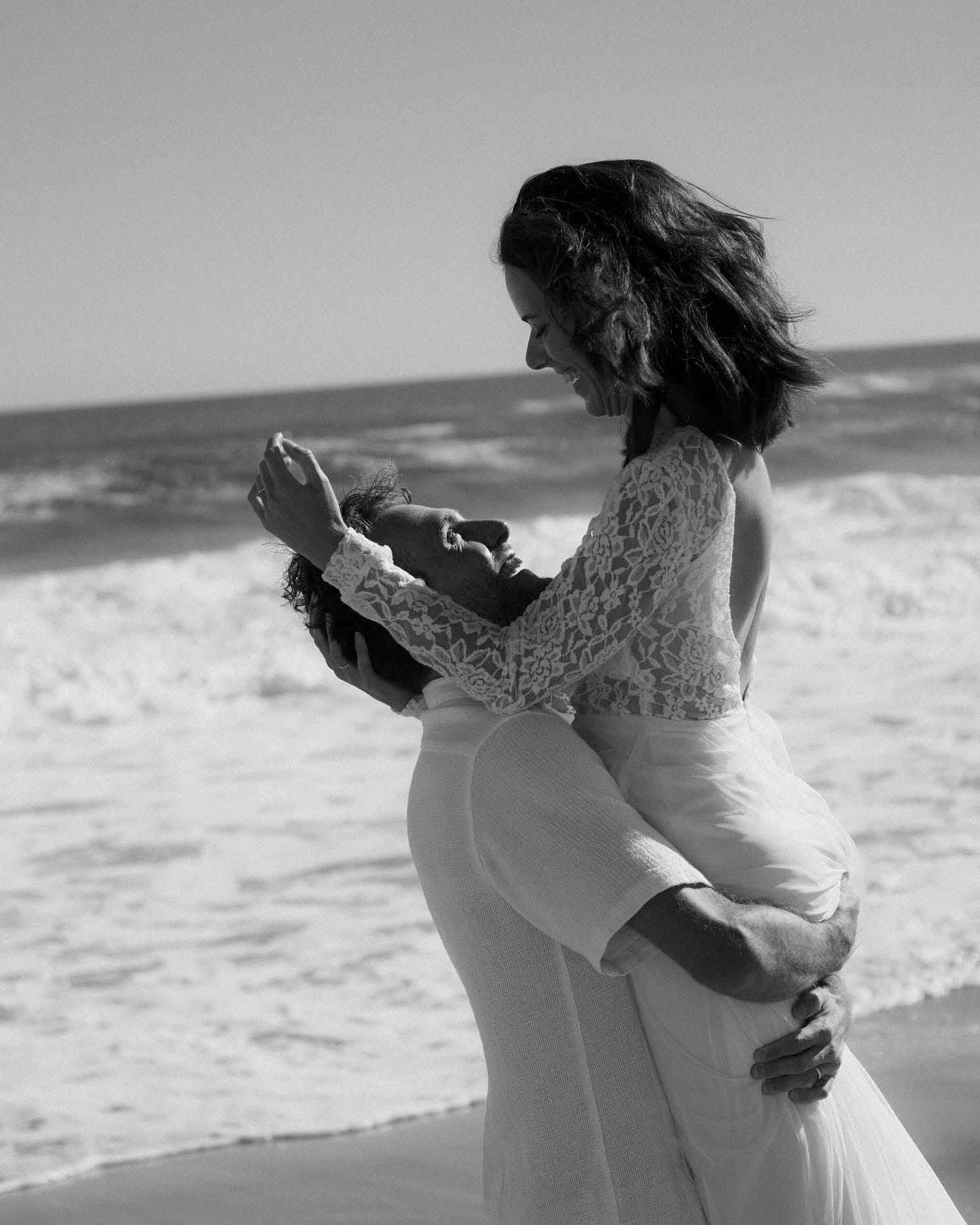 Couple embracing on beach in wedding attire, Garden Route cinematic wedding film