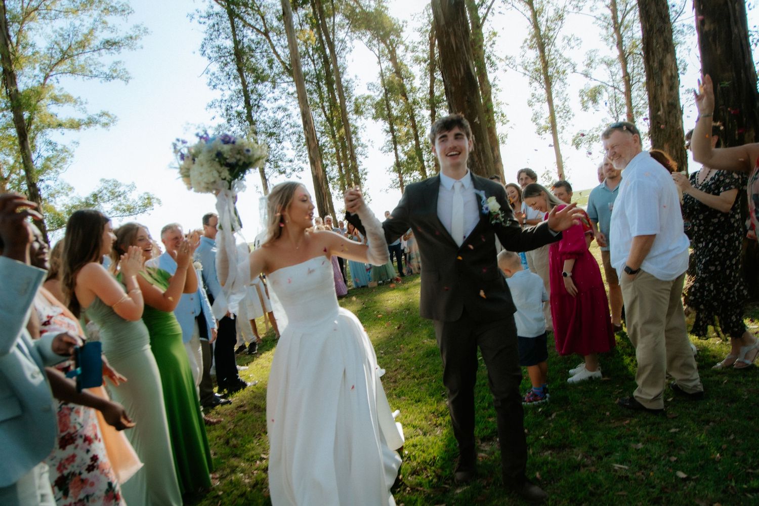 Bride and groom walking outdoors at Garden Route wedding with guests applauding