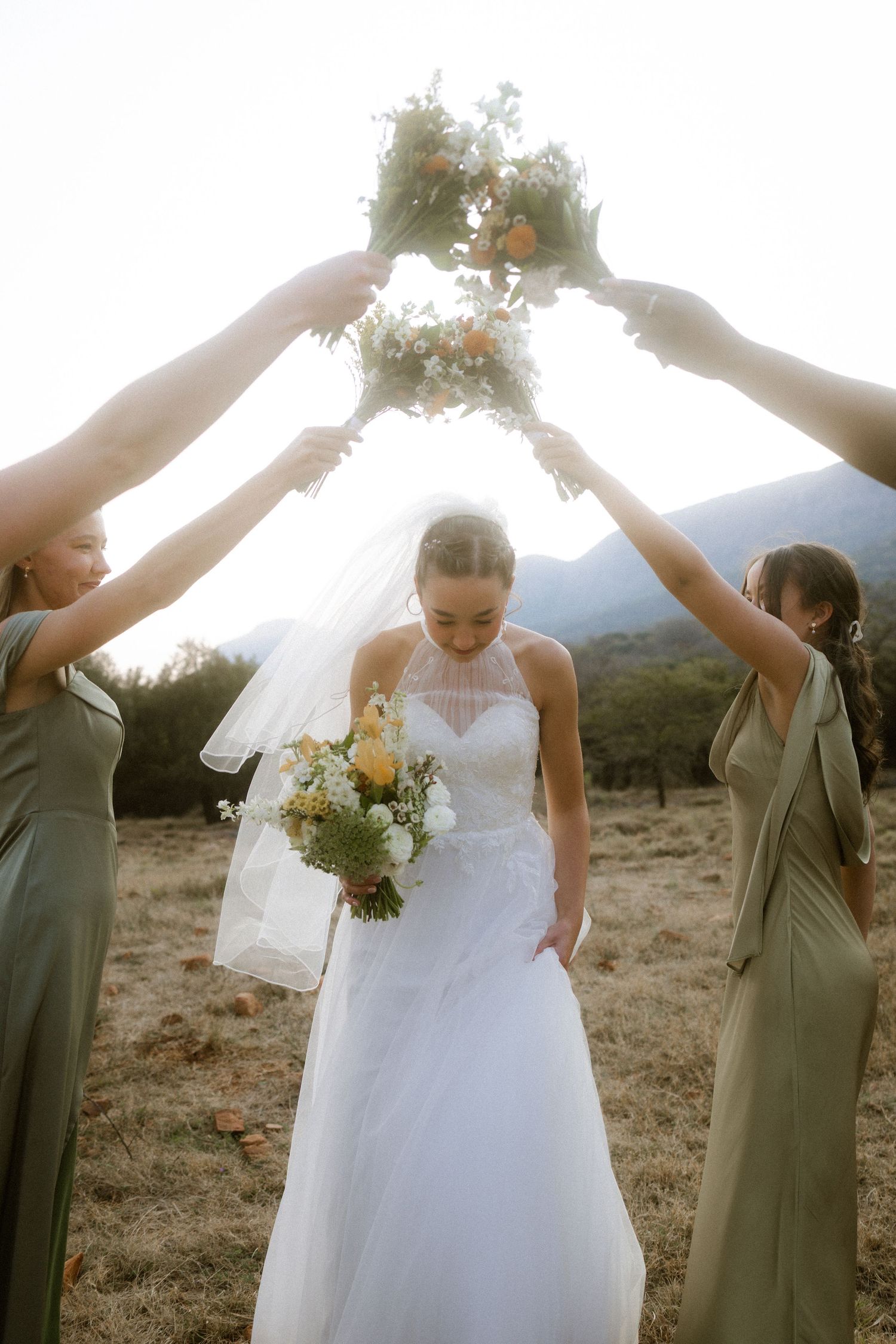 Bride with bridesmaids holding bouquets above her in Garden Route wedding photo