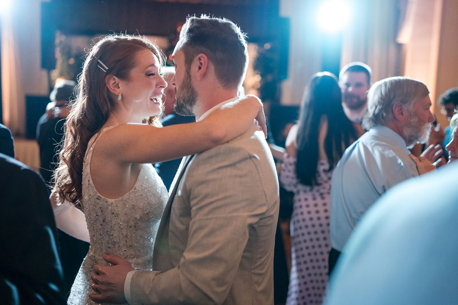 Bride and groom sharing their first dance at a wedding reception, smiling lovingly at each other.