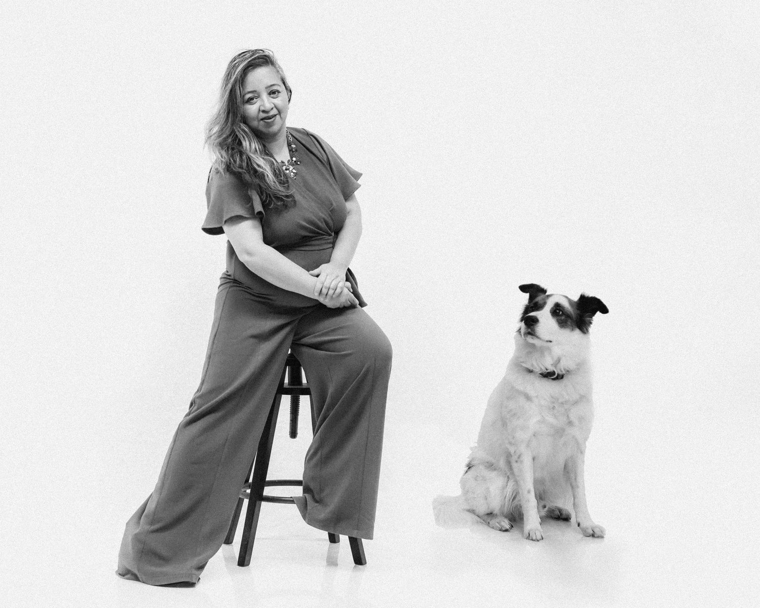 A black and white studio portrait of Anu Kalle with her dog Bandit looking at her adoringly.