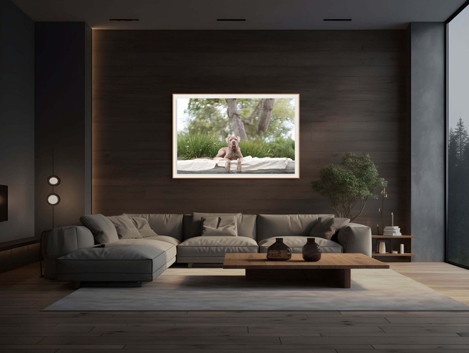Modern dark wood living room interior mockup featuring a large framed canvas print of a dog in outdoor setting, above a grey sectional sofa.