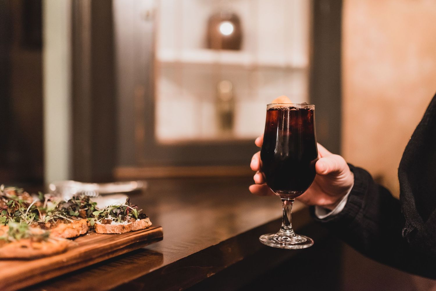 Sage + Cinder Mukilteo woman's hand holding beverage near buffet of vegan appetizers