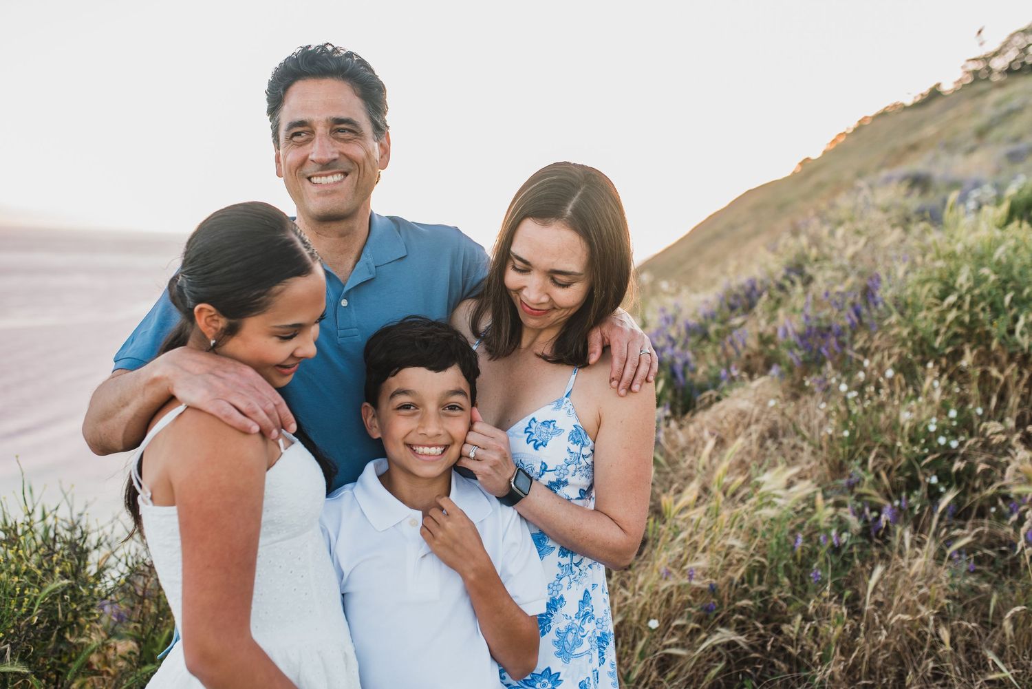 Family enjoying candid moments together during a sunset photoshoot on a scenic coastal hillside at Ebey's Landing on Whidbey Island.