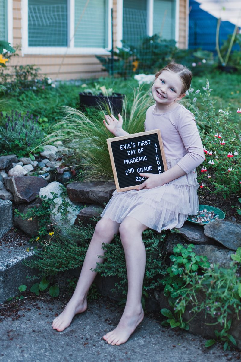 girl sitting in yard with back to school sign