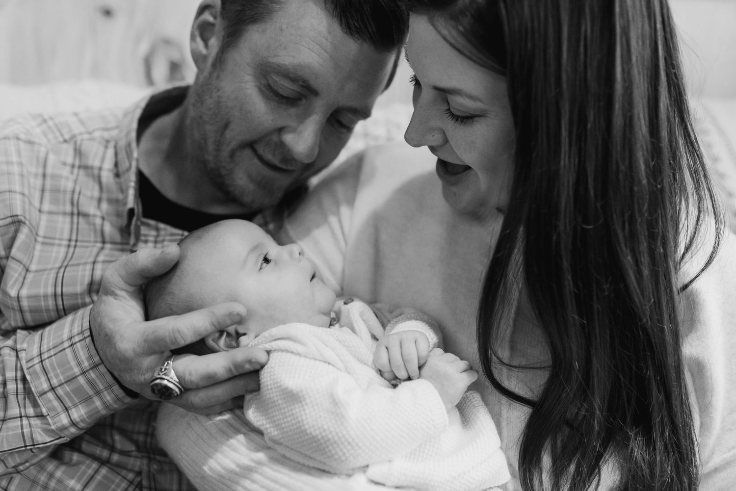 A series of black and white photos showing tender moments between parents and their newborn baby.