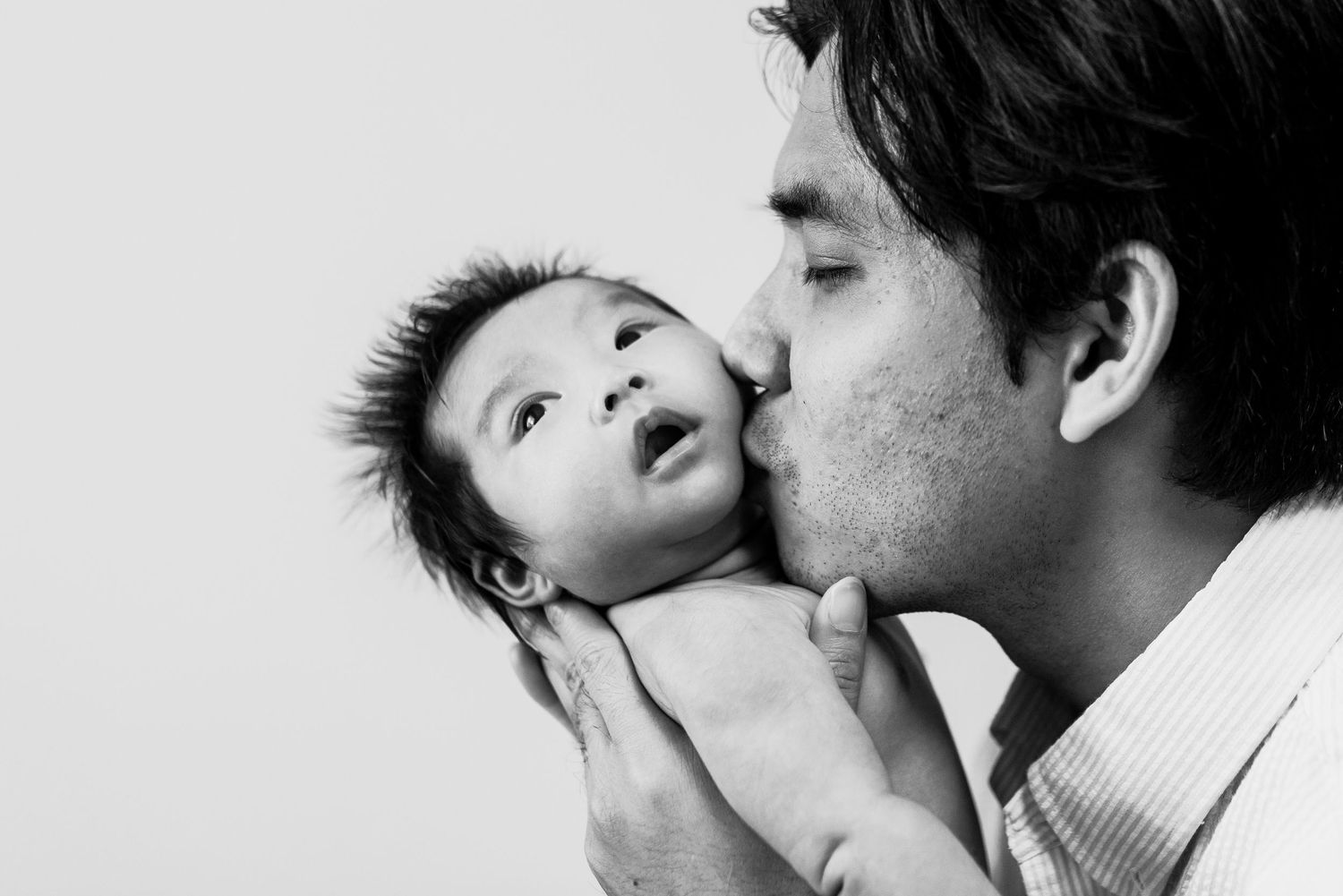 A tender romantic moment between two people sharing an intimate kiss against a white background.
