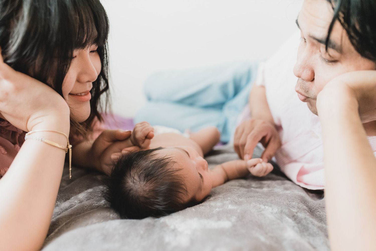 A newborn baby sleeps peacefully while being held by a caregiver in a soft, intimate setting.