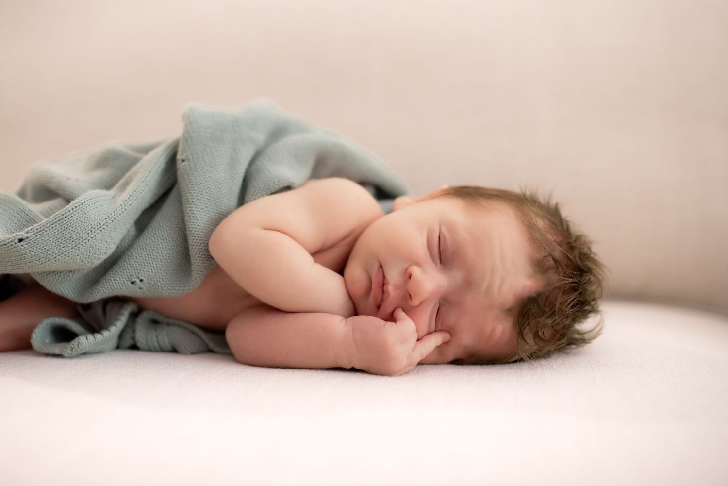 A series of soft, minimalist newborn photography poses showing a sleeping baby on light beige fabric.