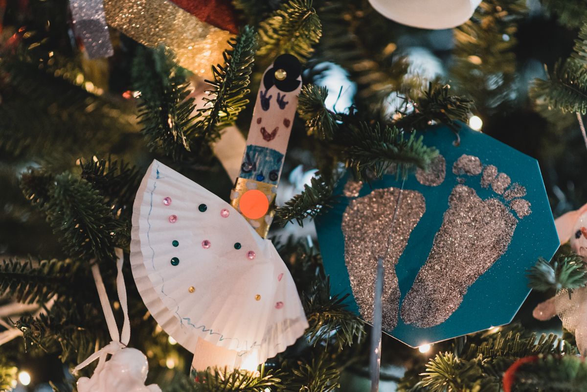 Handmade Christmas ornaments and decorations hanging on tree with lights.