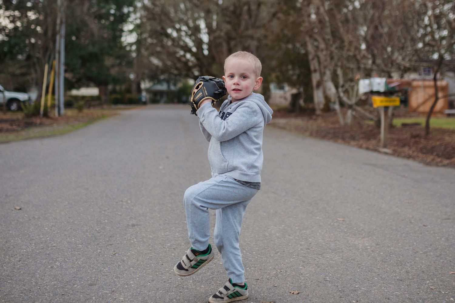boy throwing a baseball in the middle of the street
