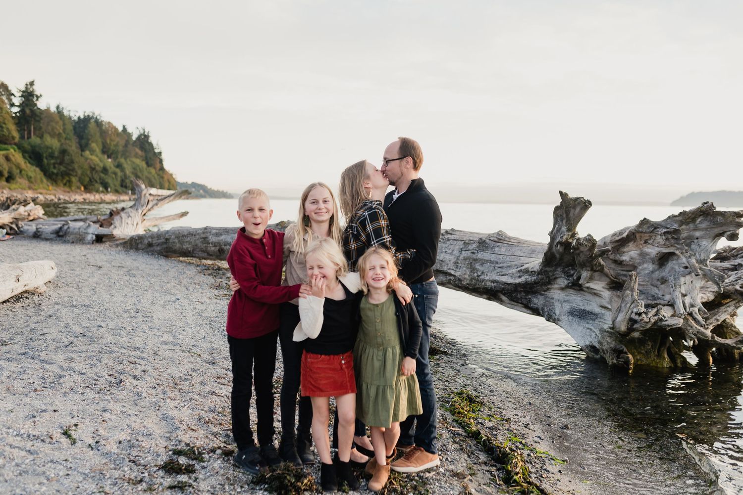 Family gathering on a rocky Pacific Northwest beach during golden hour with ocean waves and cliffs in the background.
