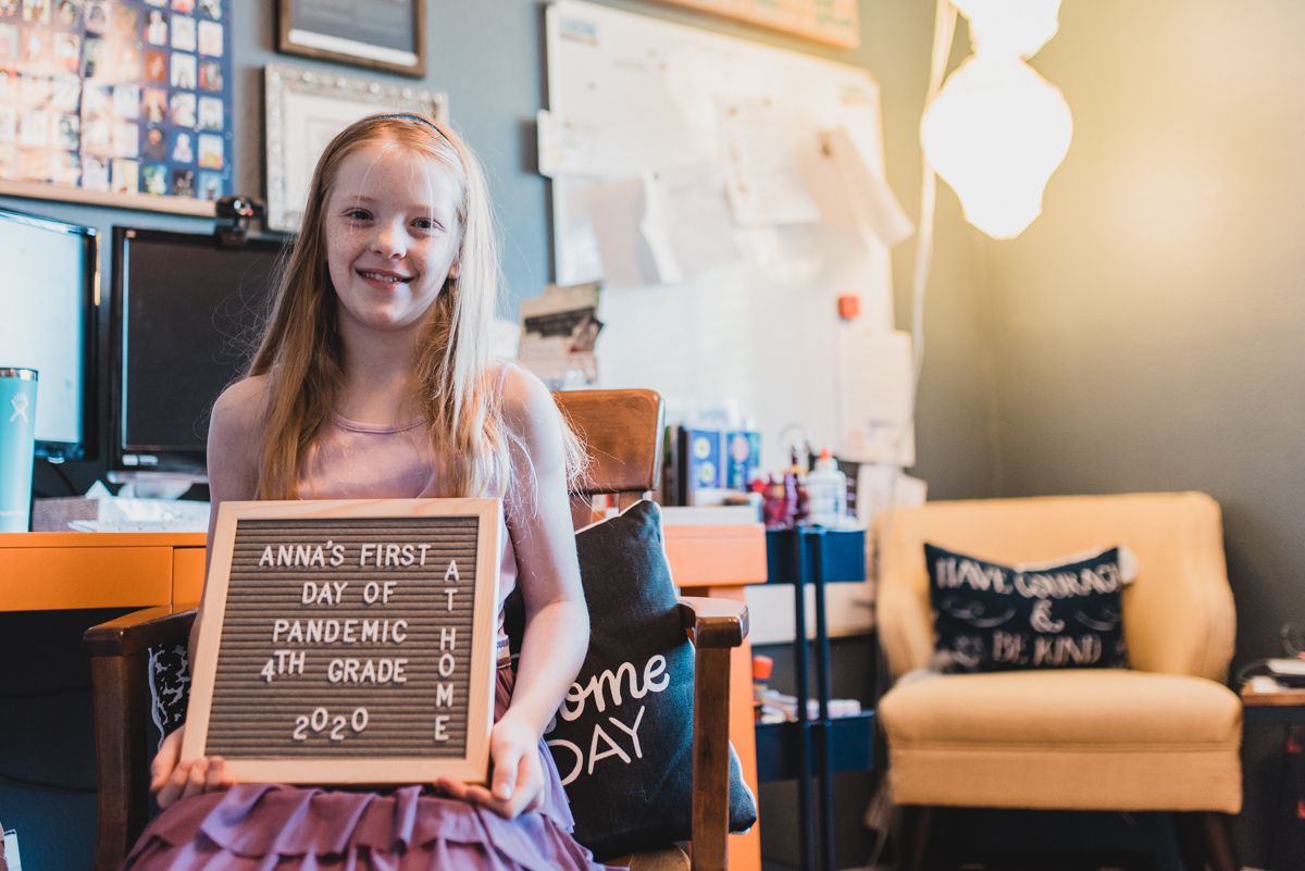 girl at desk with first day of school sign