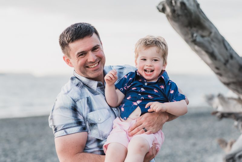 A joyful moment captured at the beach with a plaid shirt and a small child wearing a blue patterned shirt.