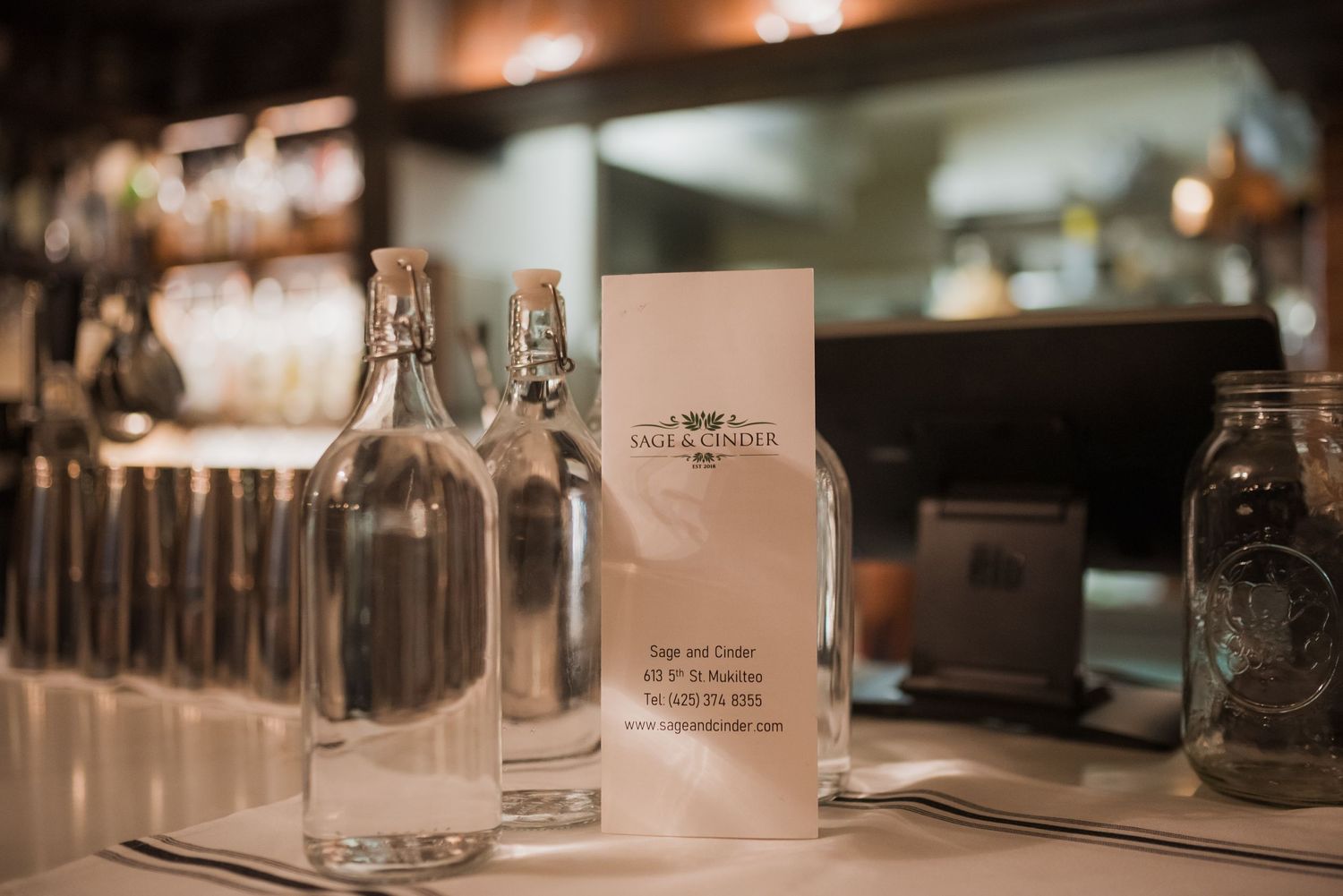 Sage + Cinder Mukilteo water bottles and menu on bar