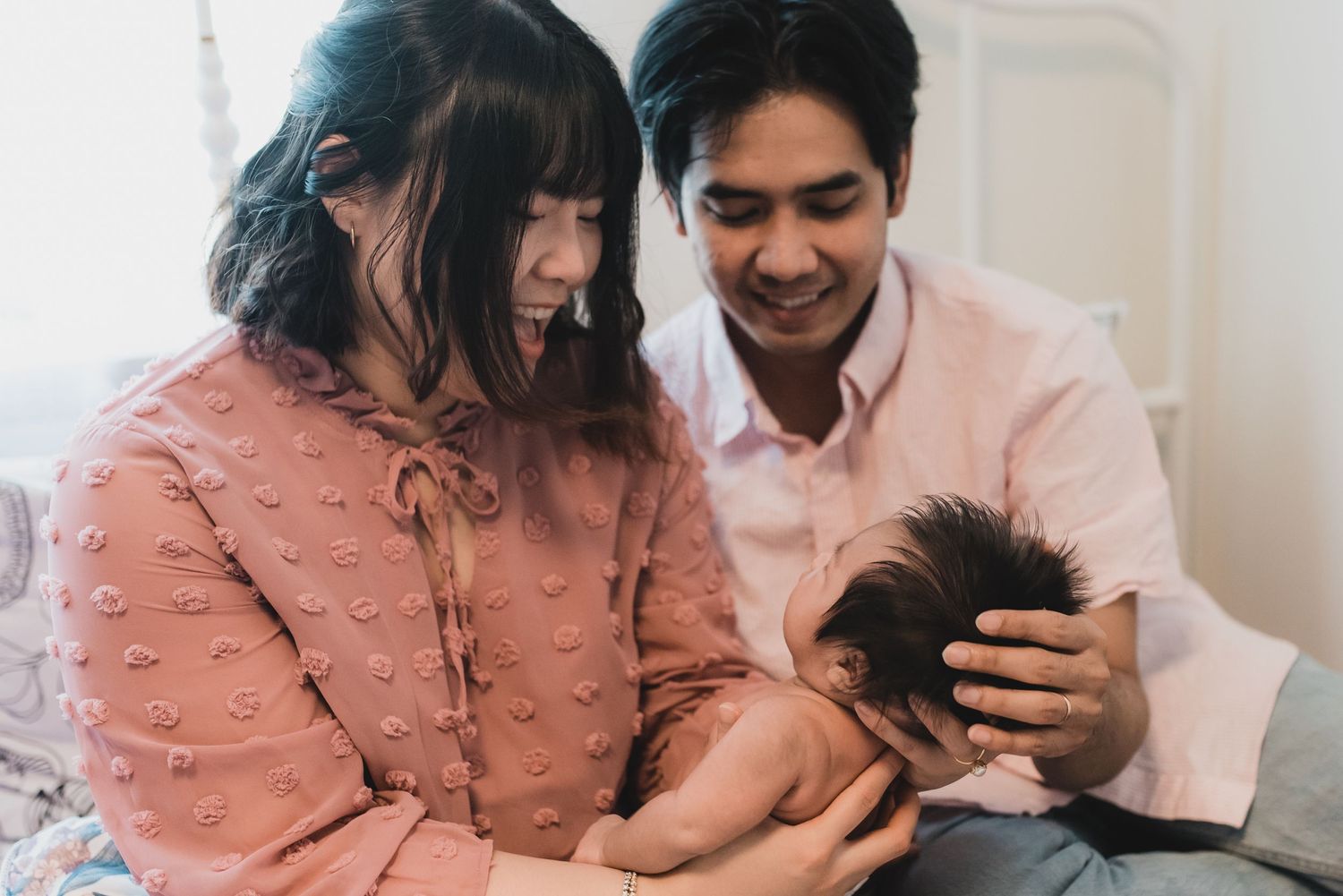 mom and dad holding and smiling at their new baby girl in their home
