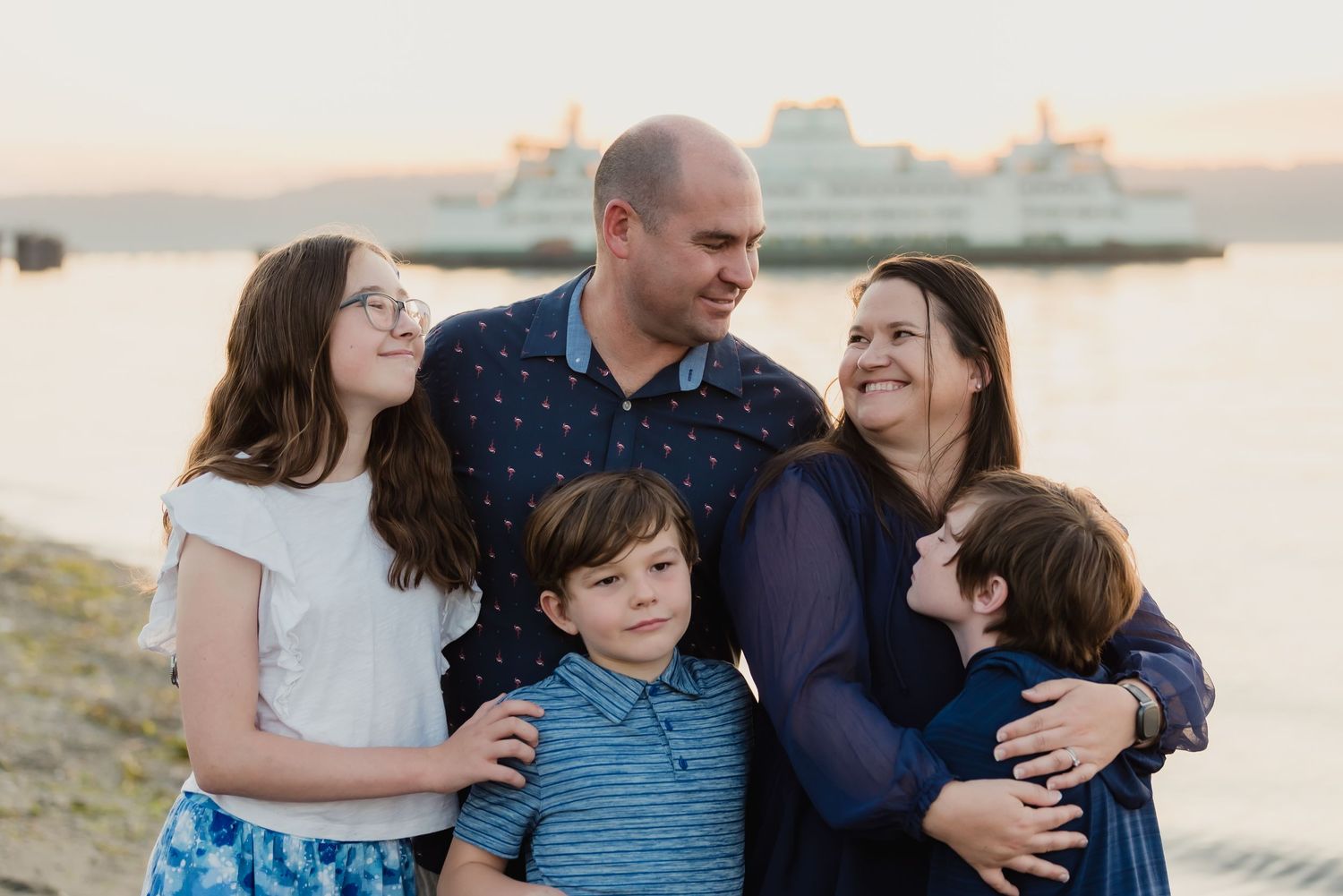 A family shares tender moments together during a sunset photoshoot on a beach.