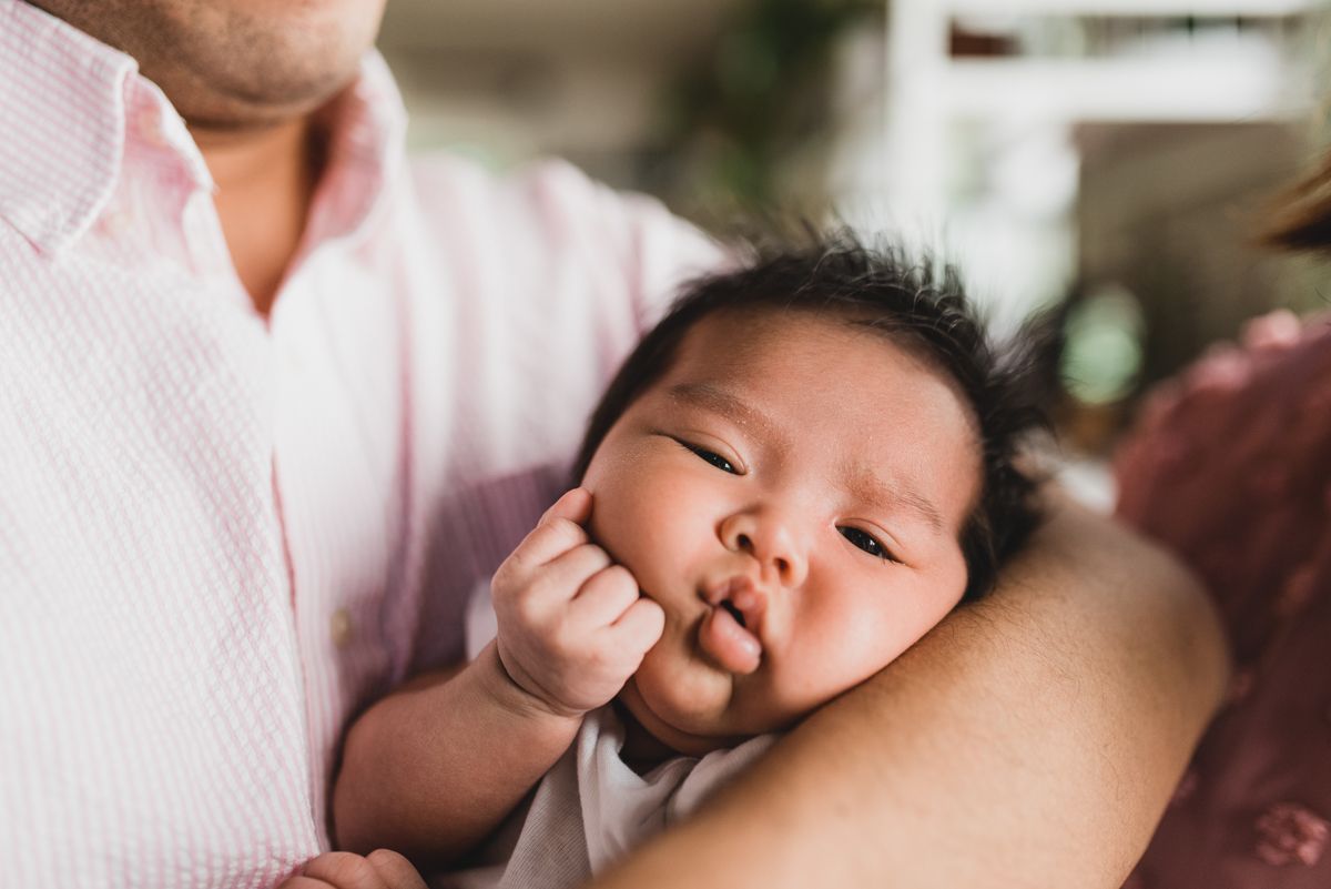 Close-up of a sleeping baby being held in someone's arms.