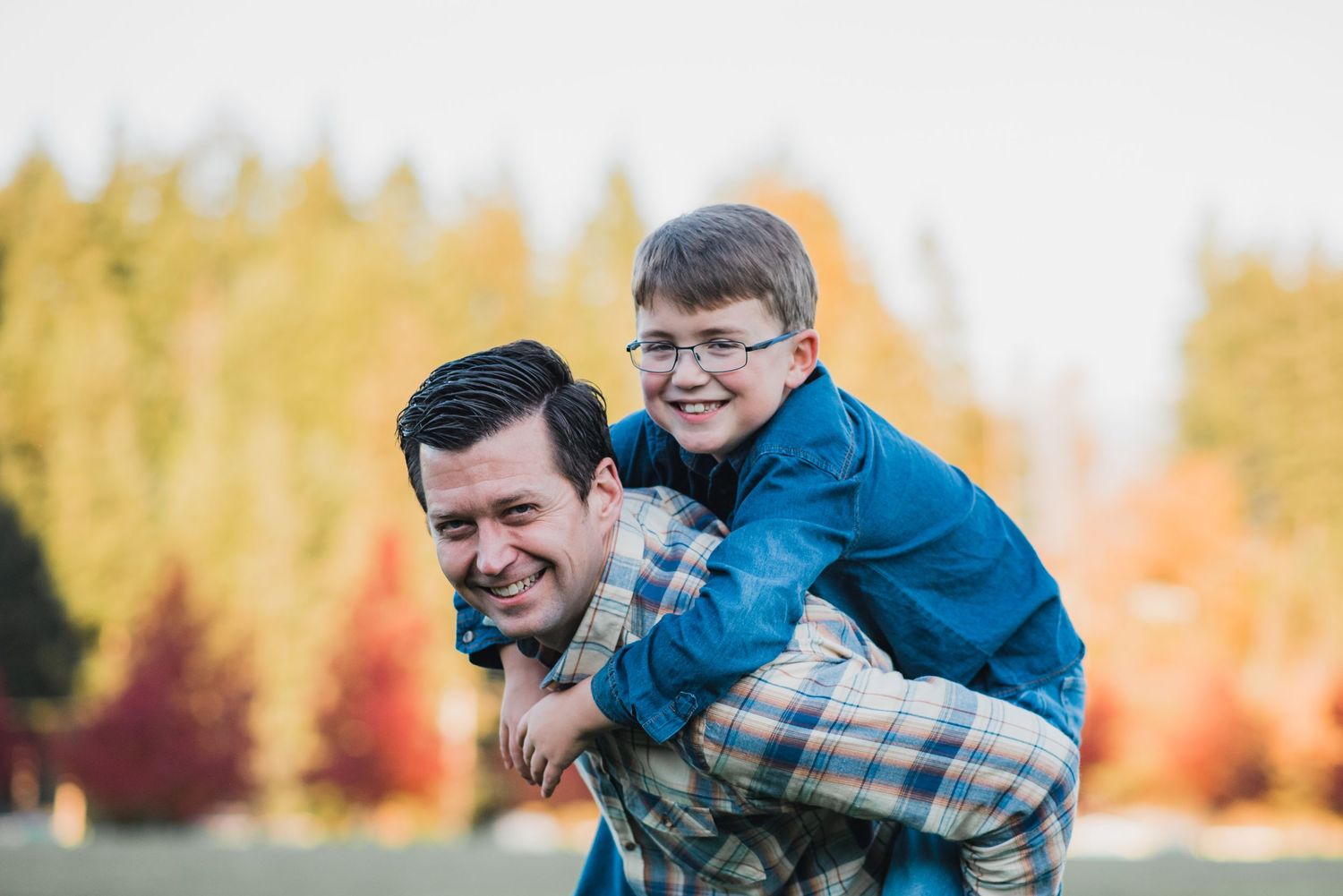 dad giving son a piggyback ride amid fall color