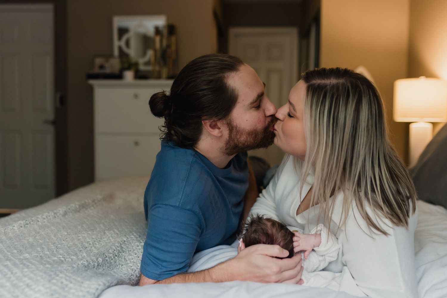 A couple sharing an intimate moment together on a bed while holding a chocolate cupcake.