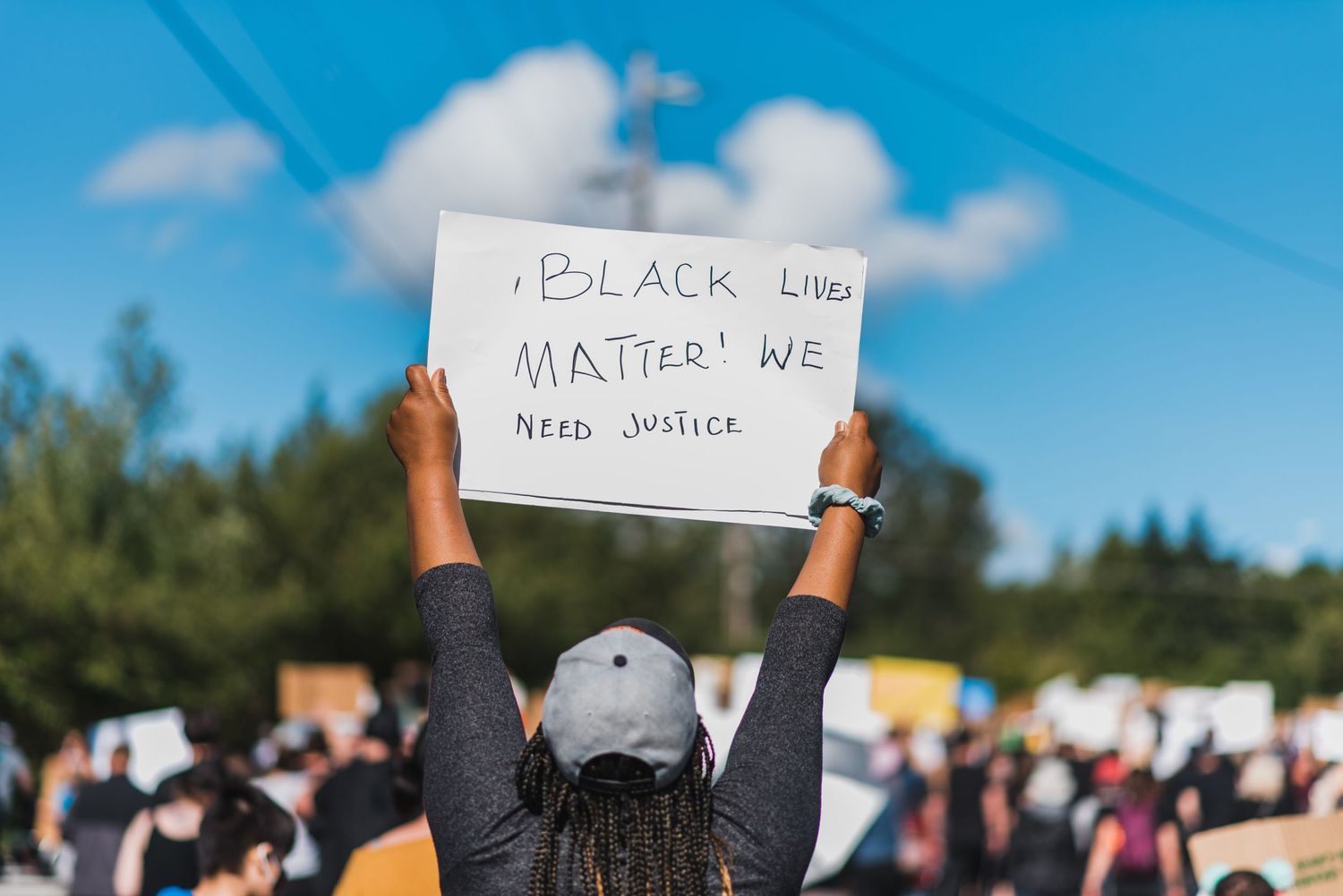 Black Lives Matter We Need Justice sign held overhead in Mukilteo