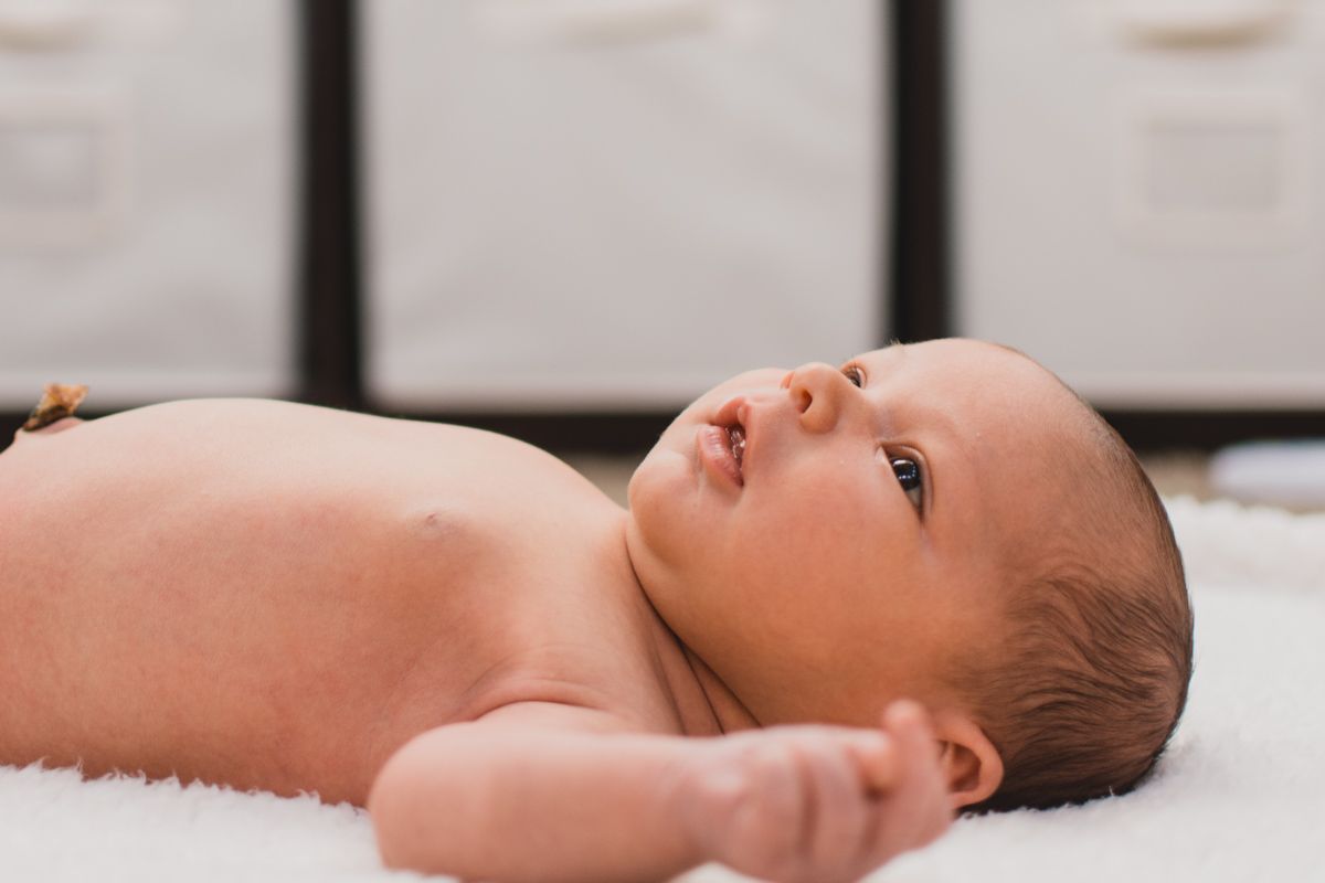 baby boy laying on his back with arms out