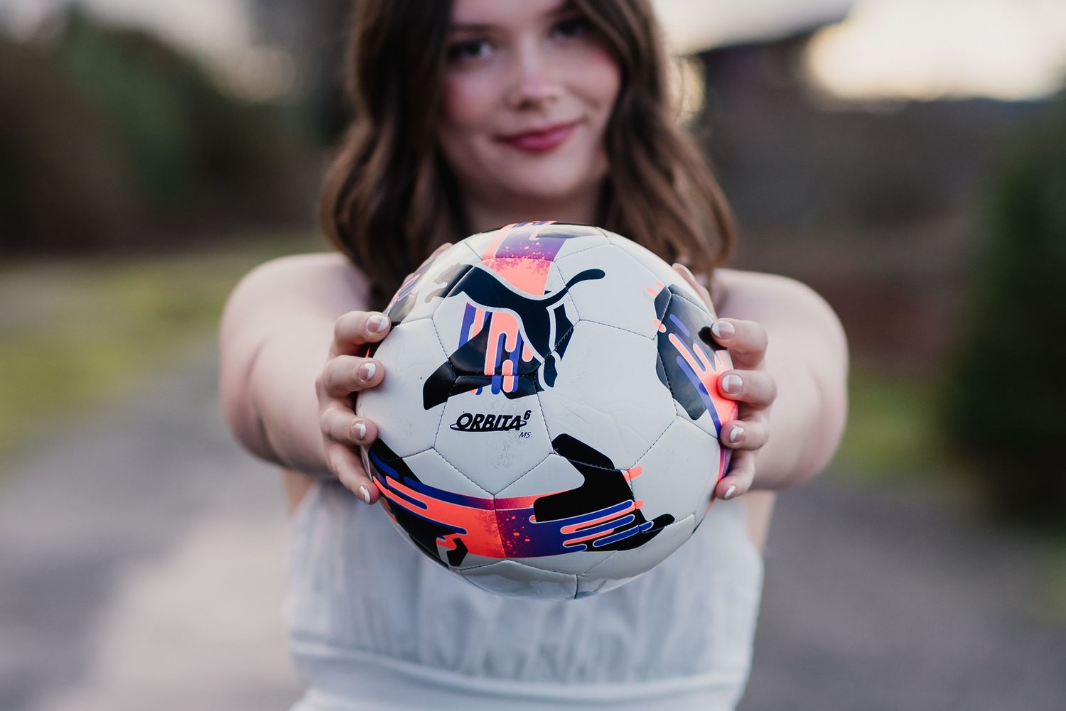 Person holding white and red soccer ball with both hands in various poses against outdoor backgrounds.