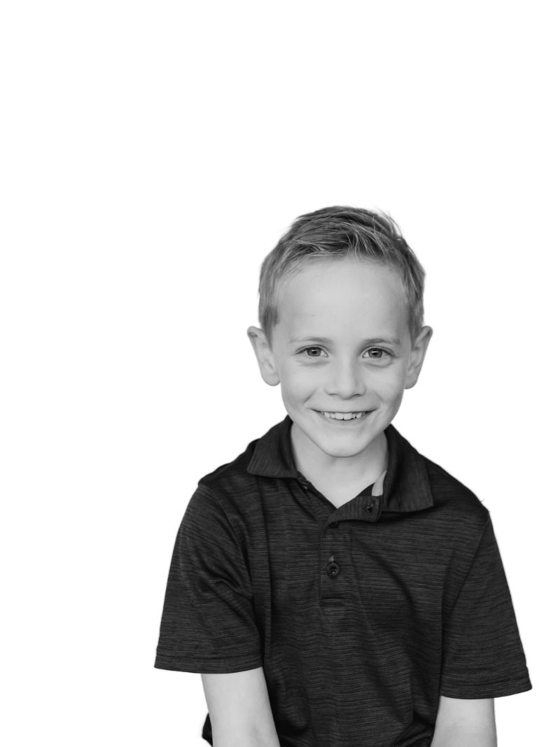 Black and white portrait of a smiling young boy with short hair wearing a polo shirt.