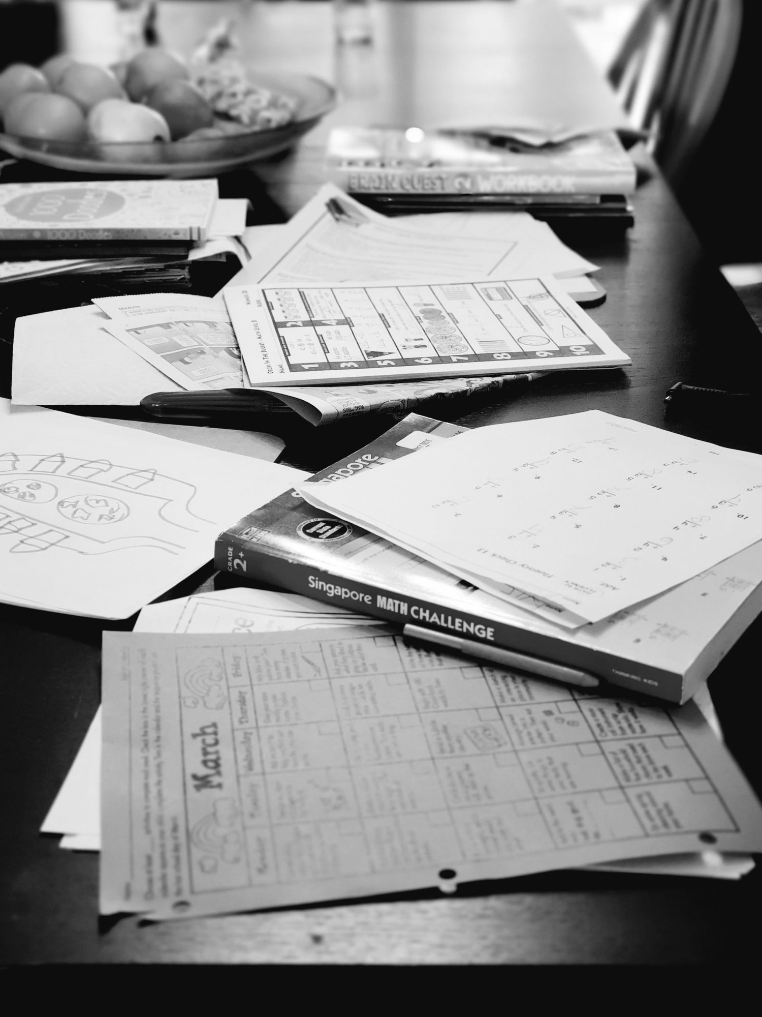 black and white photo  of children's schoolwork scattered on a table