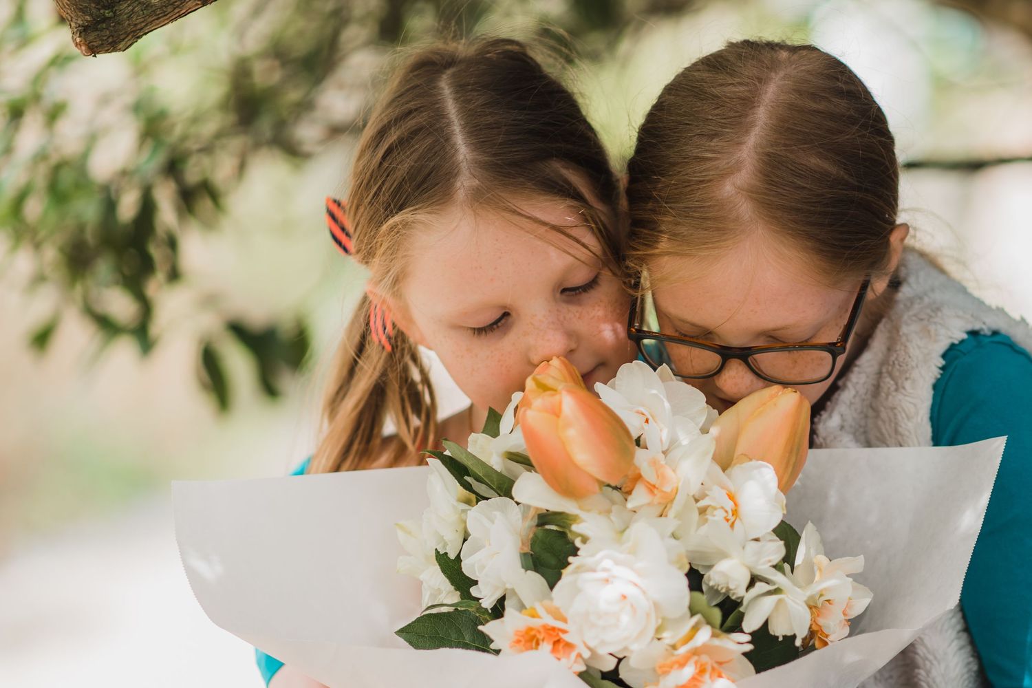 Mukilteo, Washington two young girls smelling a bouquet of daffodils and tulips