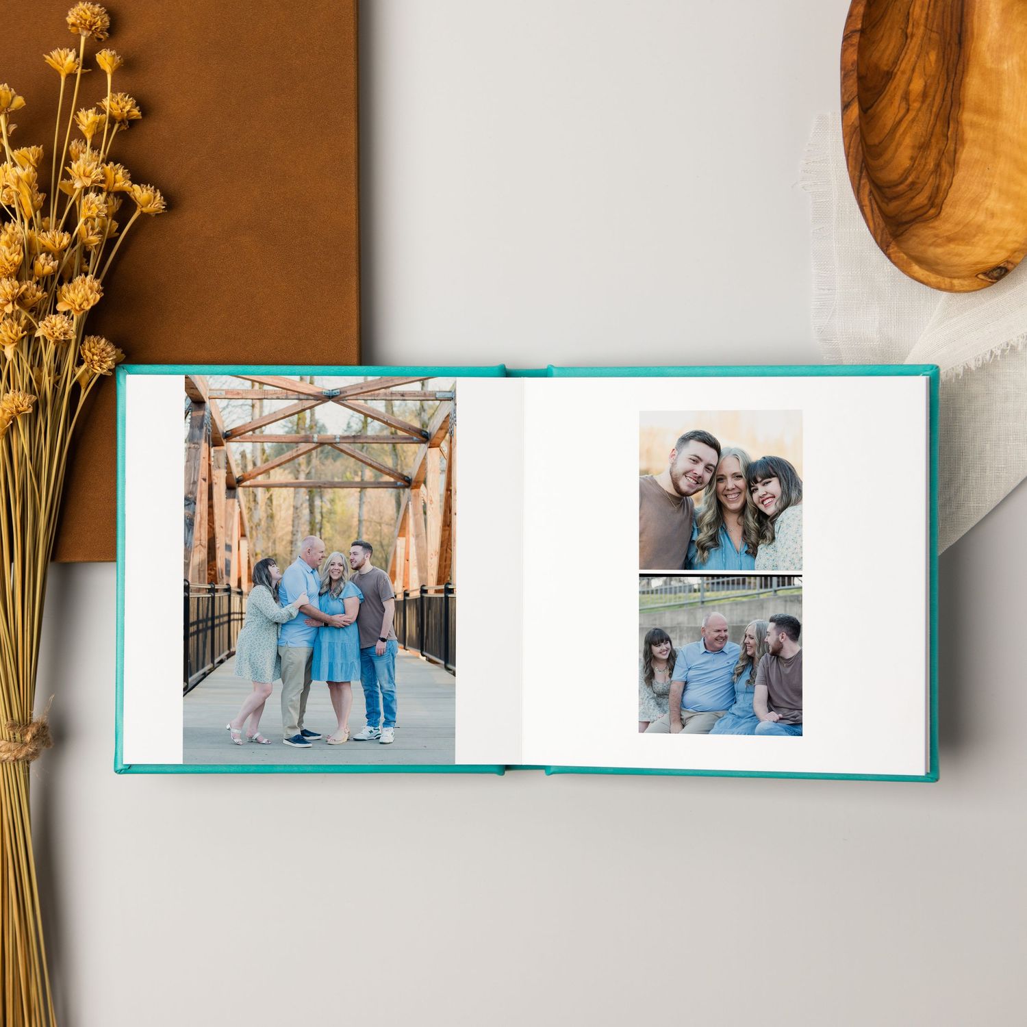 Photo album pages displaying family moments with wooden decor elements and dried flowers on a brown background.
