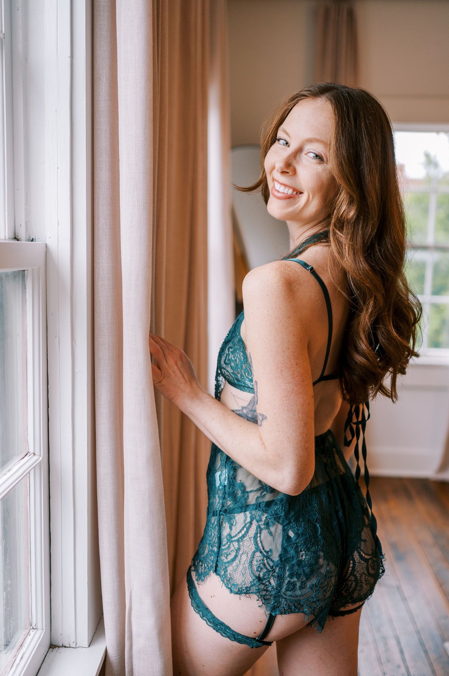 a redhead with green lace lingerie poses for luxury boudoir photos