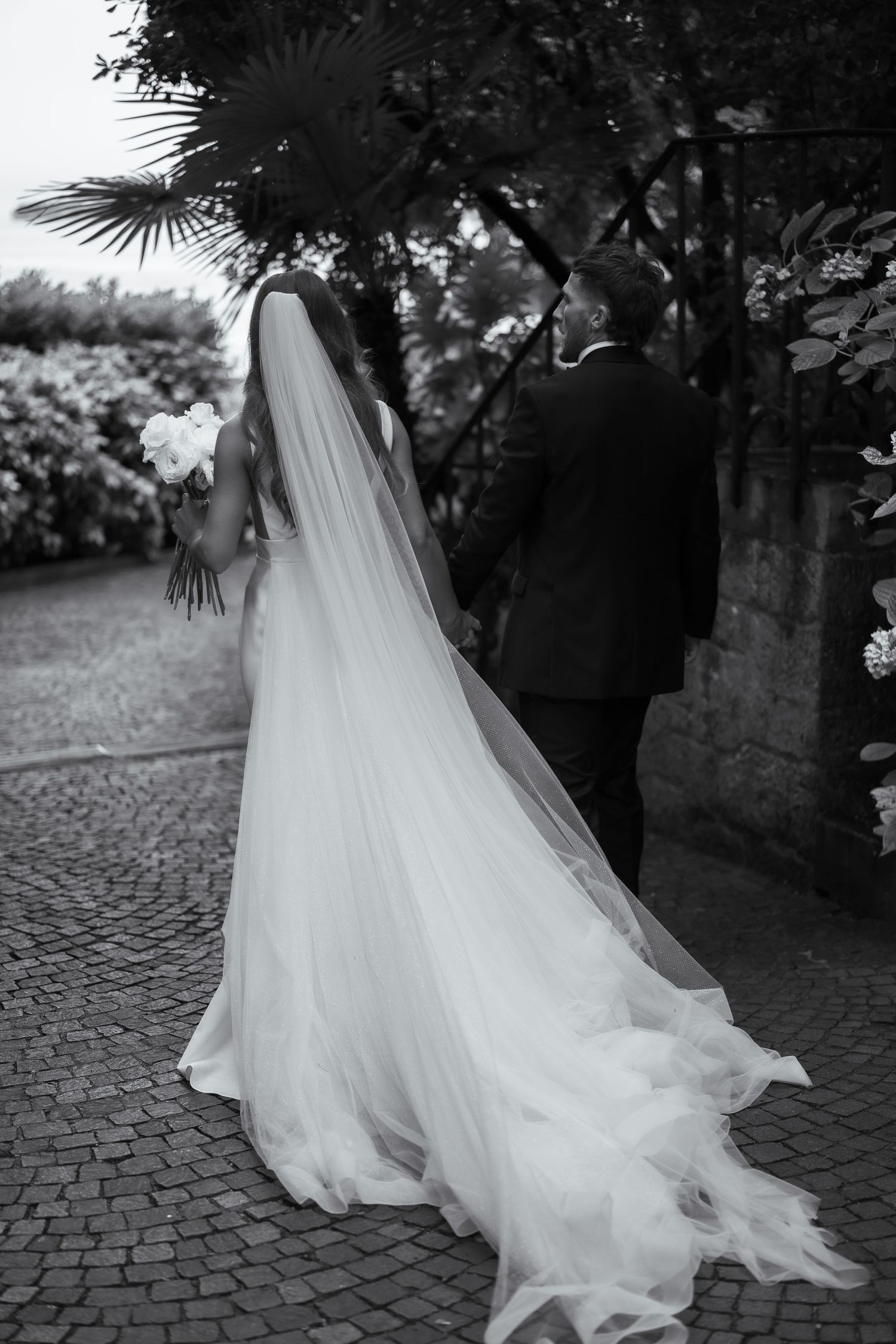 Black and white photo of bride and groom walking away from the camera at their Lake Garda wedding in Italy